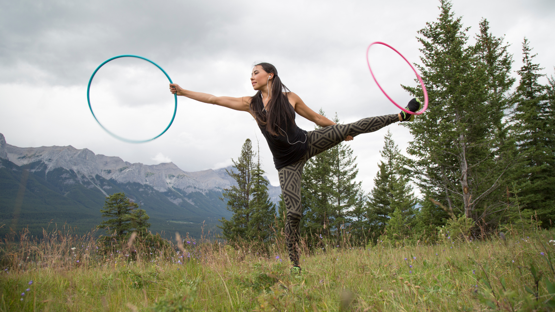 Indigenous woman hoop dancing outdoors.